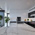 A sundrenched kitchen with sleek white cabinets and quartz countertops featuring afeat