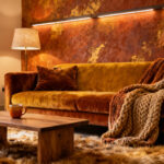 A cozy living room interior featuring deeply saturated terracotta, ochre, and caramel hues on walls, furniture, and textiles, illuminated by soft, warm ambient light, creating an intimate and tranquil atmosphere, no people.