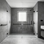 A modern aging-in-place bathroom with a zero-entry shower, wall-mounted vanity, and integrated accessibility features in a luxurious, elegant setting.