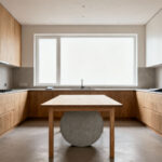 A modern kitchen interior featuring a perfectly sized dining table, allowing ample space for movement and clear pathways. The kitchen has contemporary design elements, natural light, and a spacious, uncluttered feel.