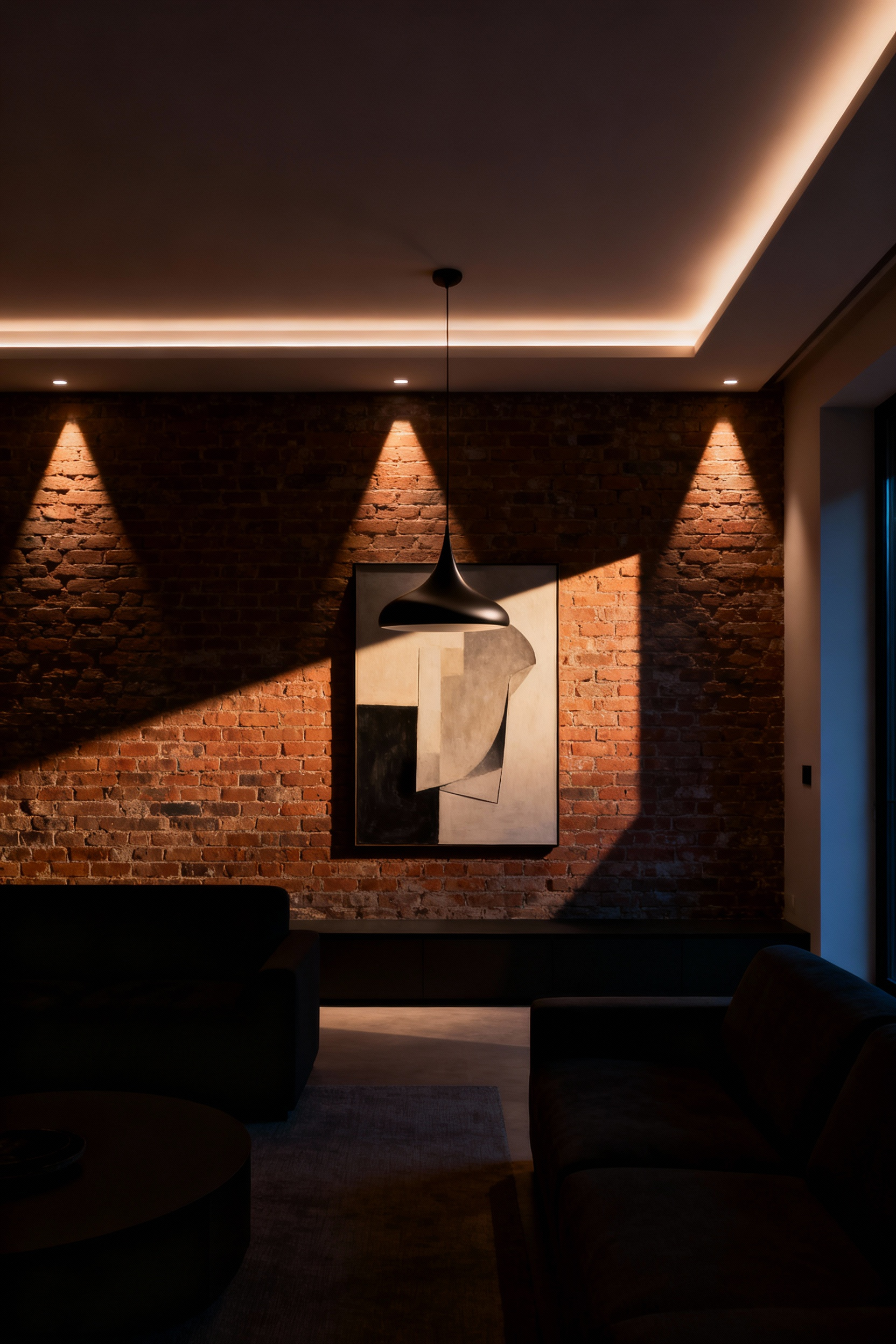 Modern living room interior showcasing dramatic shadow play, with recessed uplights illuminating a brick wall and a sculptural pendant spotlighting a central art piece, creating visual depth.