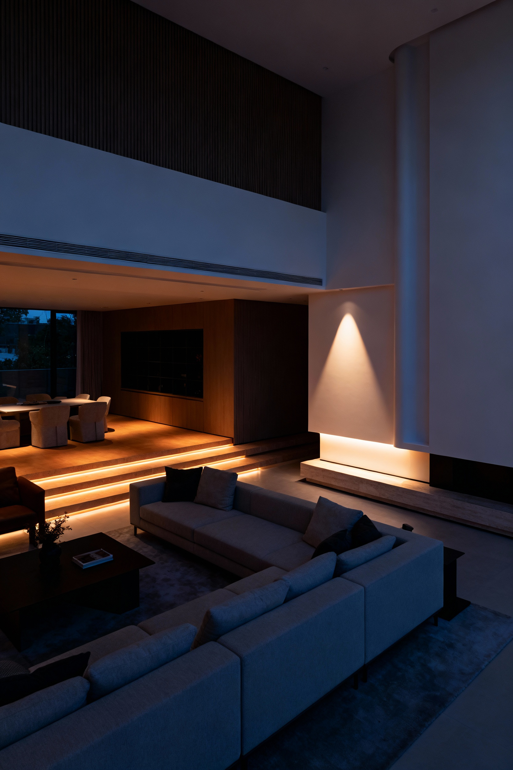 A modern living room at dusk with sophisticated, layered dynamic lighting creating a balanced and inviting atmosphere. Different light zones suggest a dynamic and programmable environment for various activities, showcasing architectural details and soft furnishings.