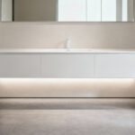 Modern small bathroom with a white floating vanity revealing continuous floor tiles, enhancing visual space and openness.