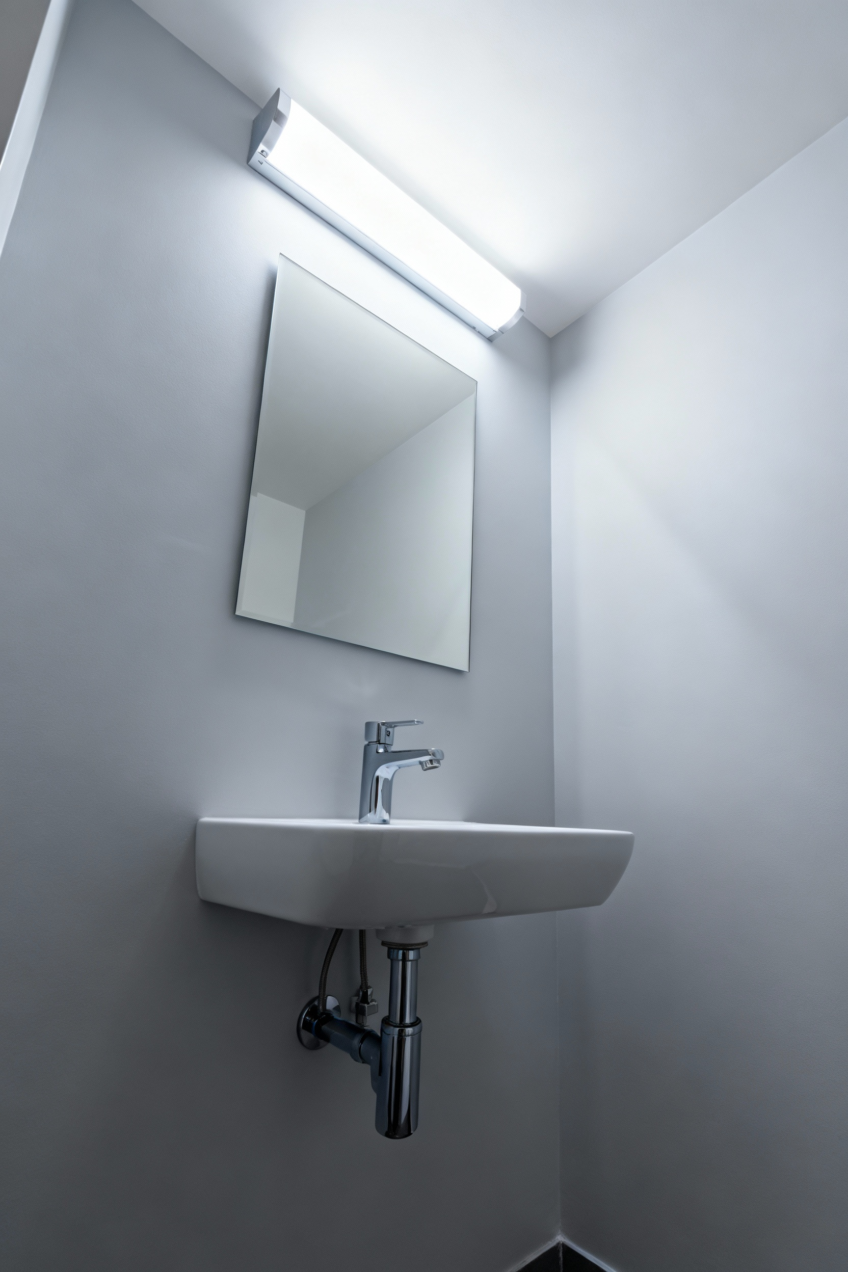 A bright small bathroom with a modern light tube providing natural overhead light above a sleek white vanity.