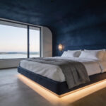 A master bedroom with a dark navy accent wall and neutral bedding designed to create a sense of psychological safety and rest.