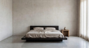 A serene, ultra-minimalist bedroom featuring a low platform bed with linen bedding, textured plaster walls, and soft diffused light, exemplifying the philosophy of aesthetic reduction.