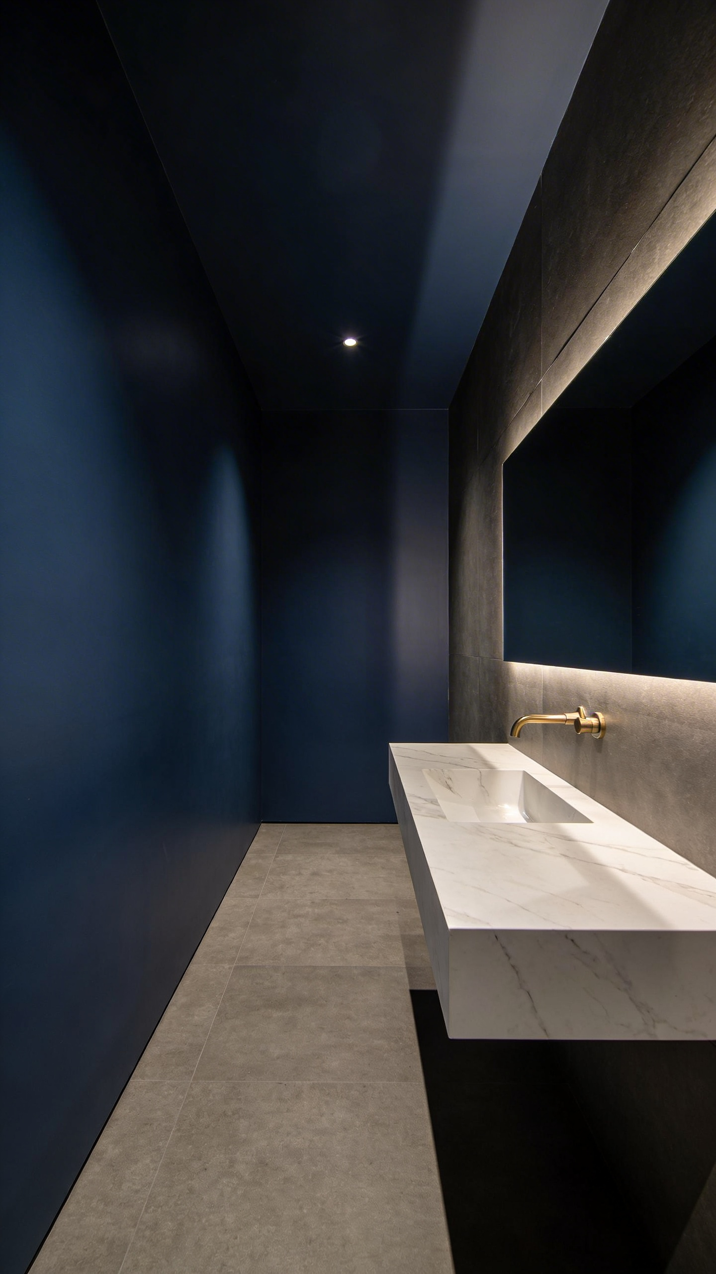 A small modern bathroom with deep navy blue walls and a white marble vanity designed to create a sense of space through dark colors.